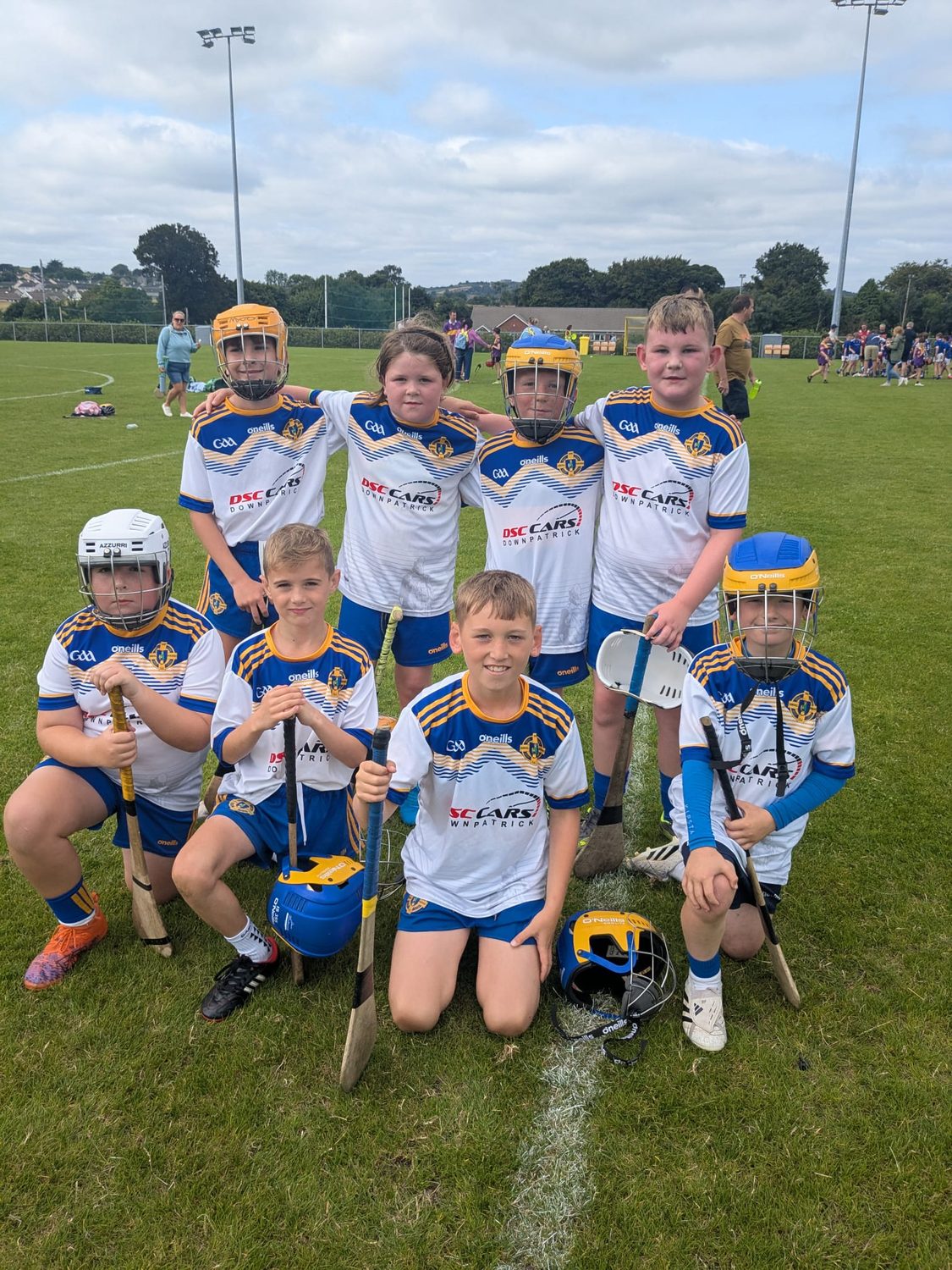 Saul GAC underage hurlers in club jerseys and helmets, holding their hurls on the pitch